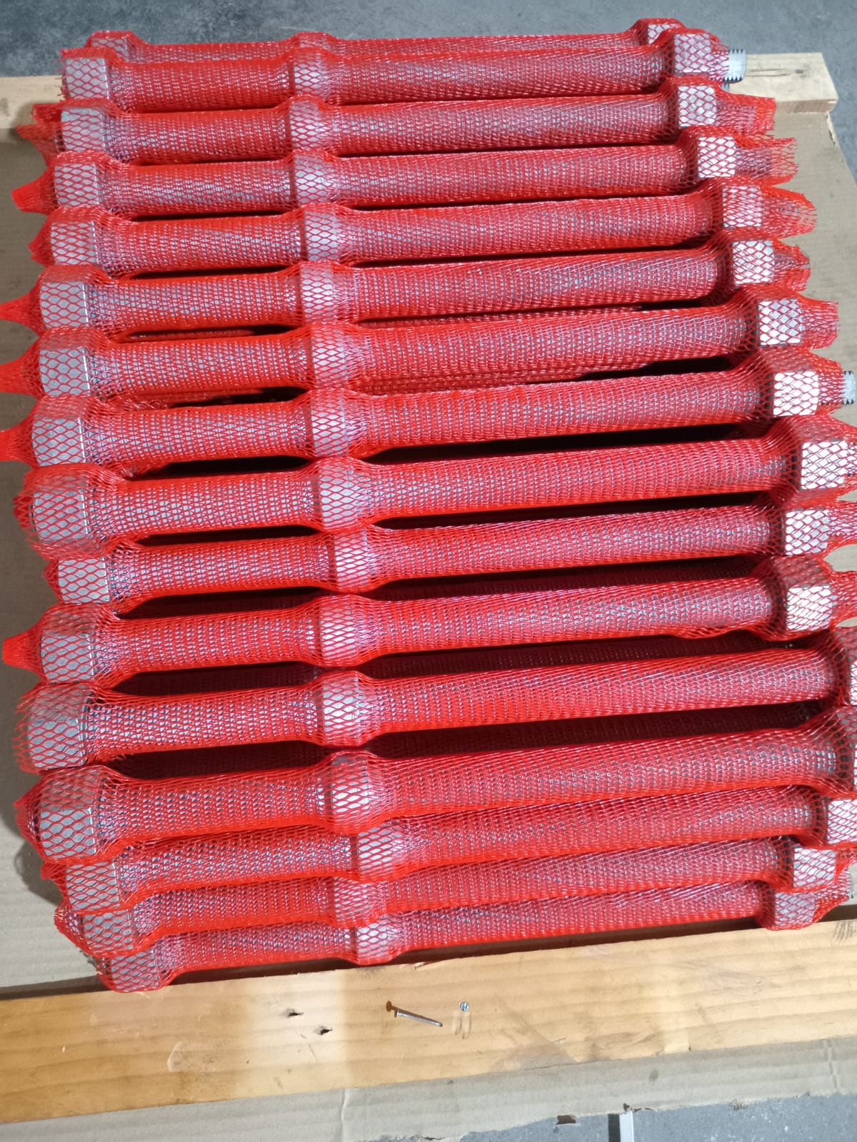 Hot-dip galvanised ASTM A193 B7M collar bolts in protective mesh sleeves on a timber pallet